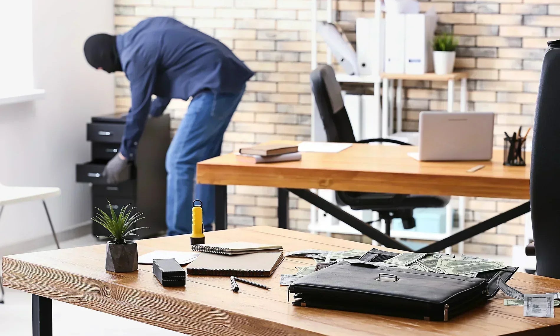 Thief opening up a file cabinet in a home office.