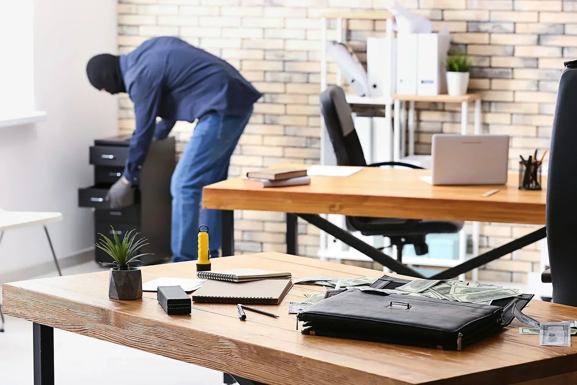 Thief opening up a file cabinet in a home office.