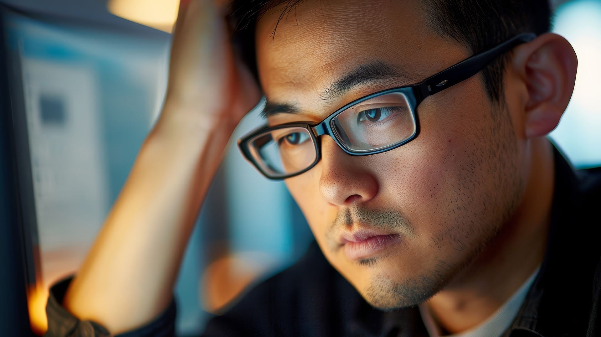 Sad Asian man staring at computer screen.