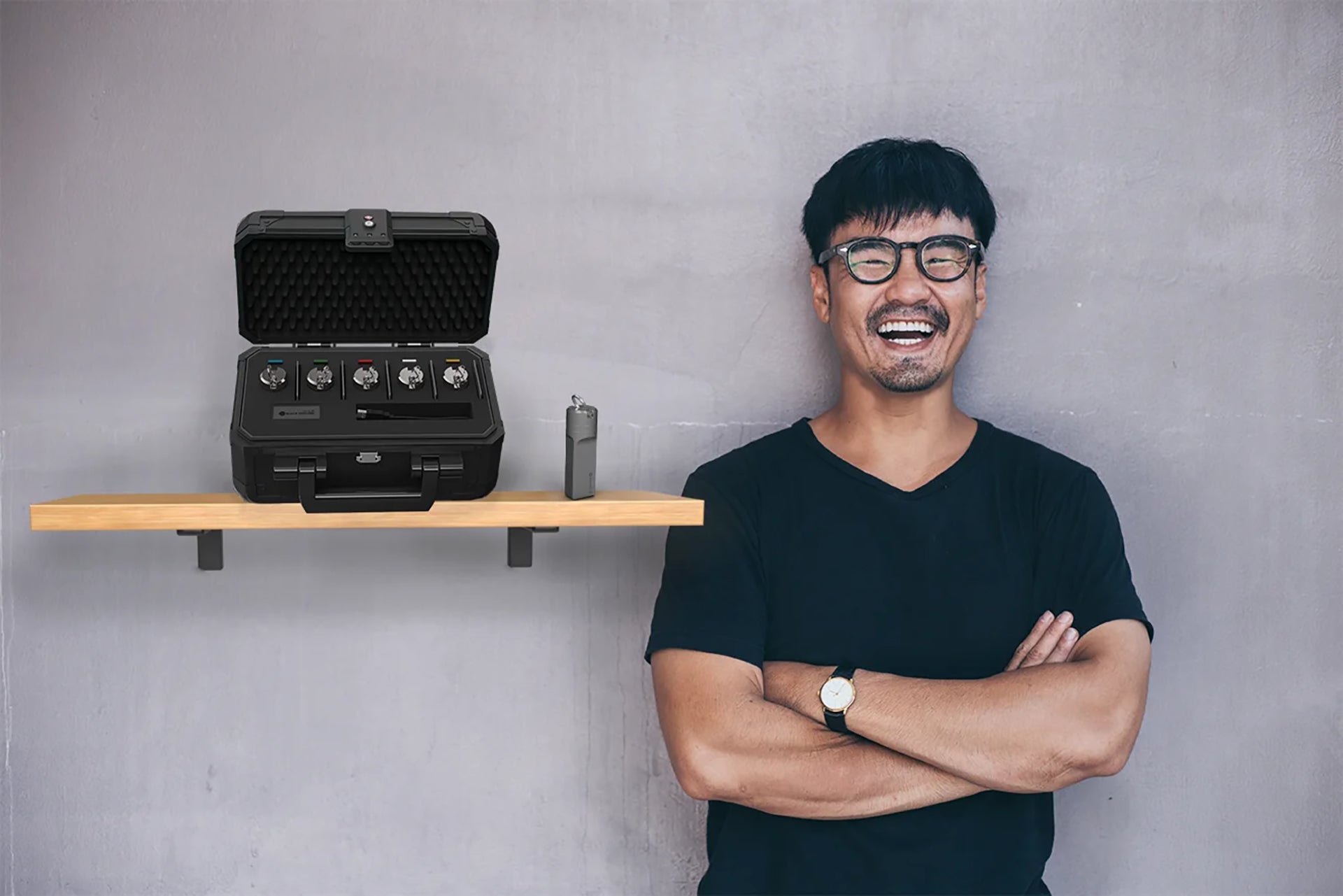 Man laughing standing next to The X Series, The BoX and The AleX atop a shelf